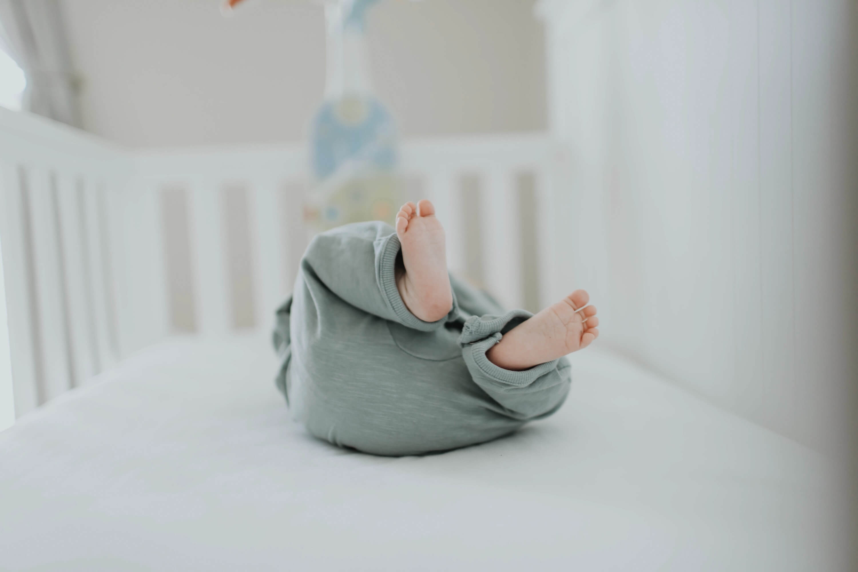 bébé dans un lit qui met les pieds vers le haut
