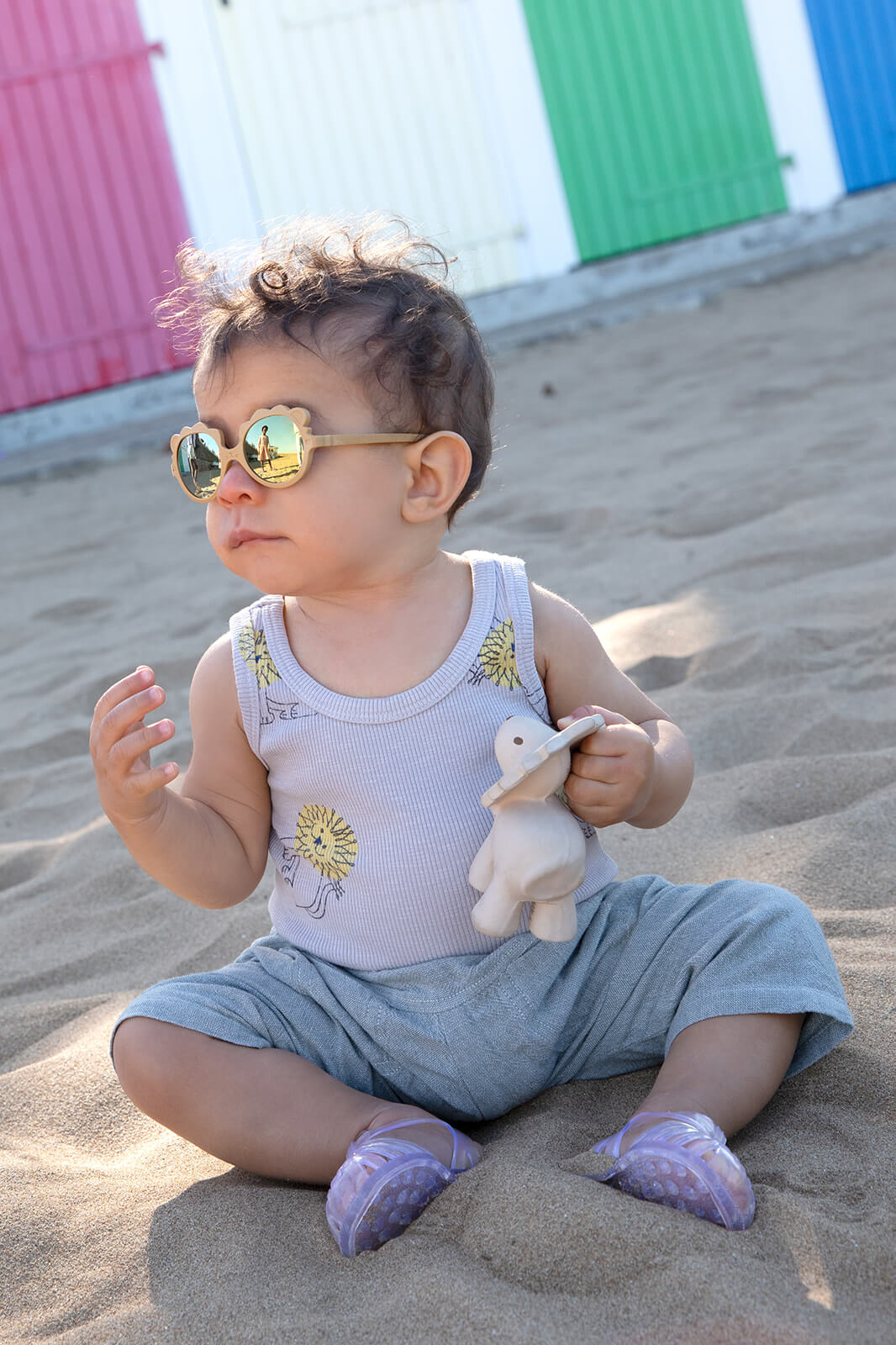 bébé assis sur le sable avec des lunettes de soleil