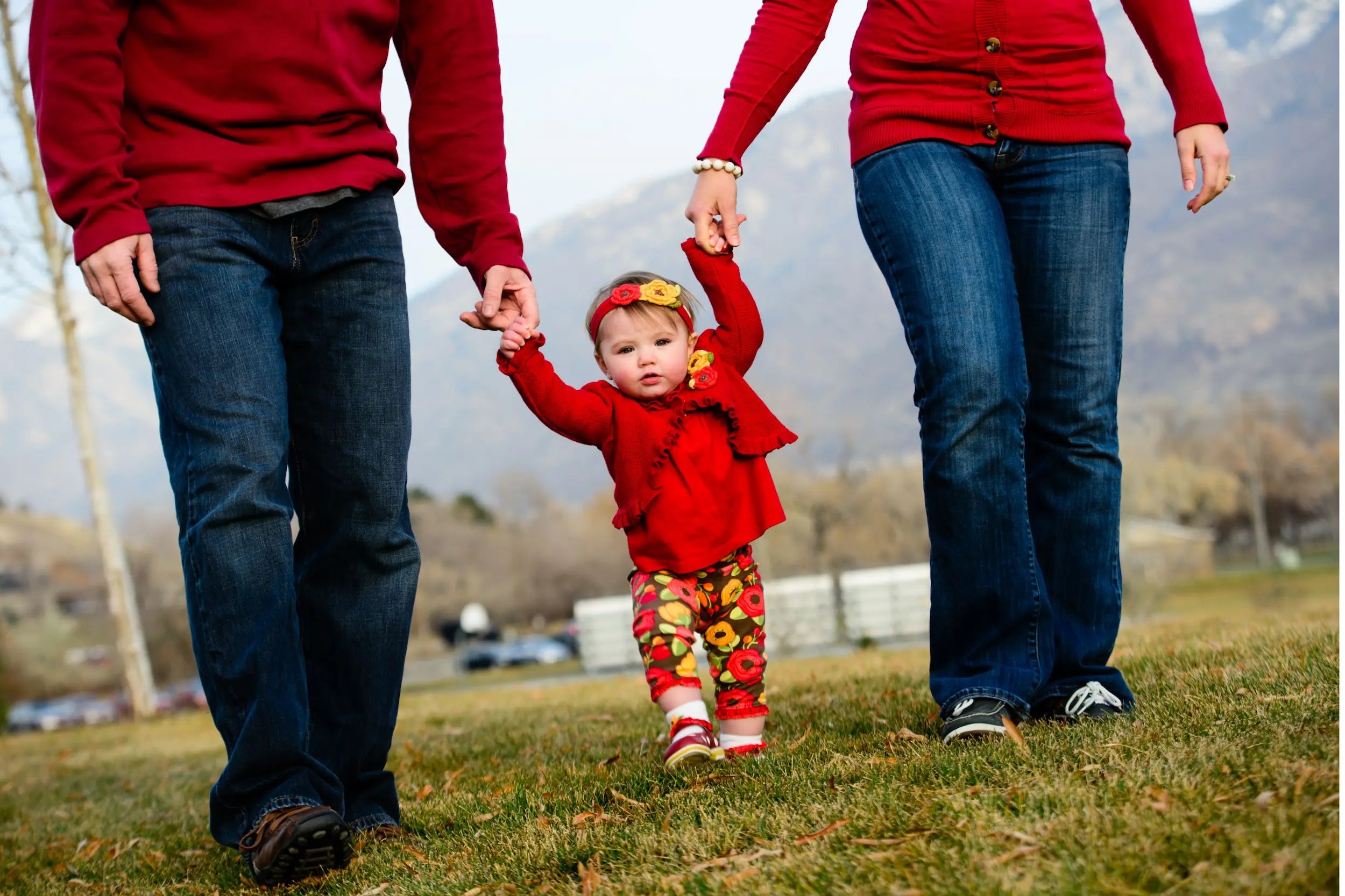 petite fille qui marche en tenant la main de ses parents tous habillés en rouge