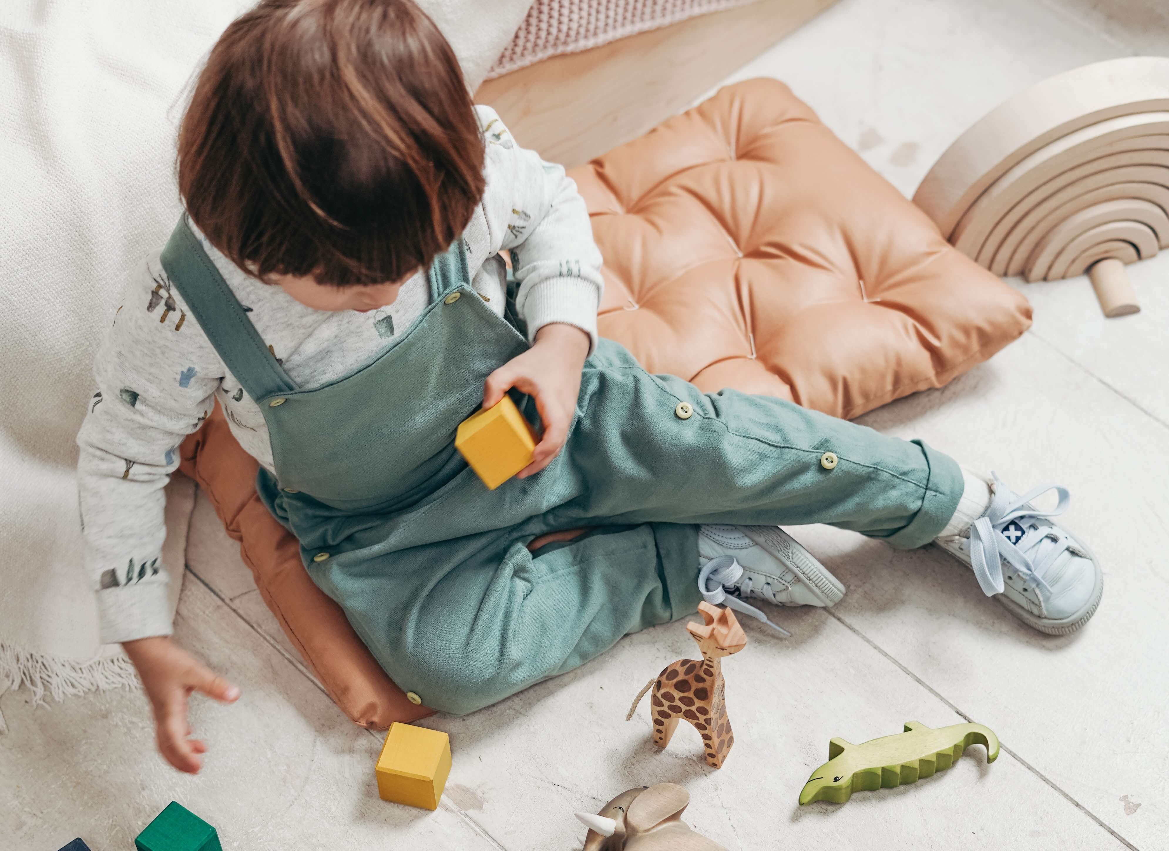 bébé en chaussures en toile jouant avec des jouets
