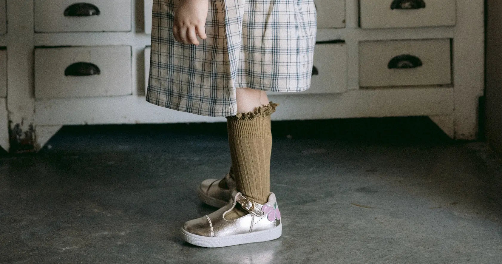 chaussures bébé de marche portées par une petite fille devant une commode